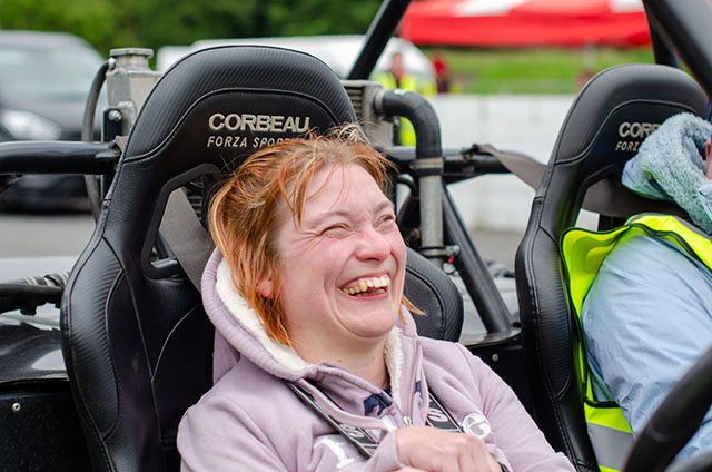 smiling woman in passenger seat at speed of sight track day