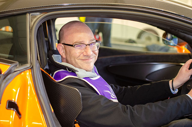 man smiling in the driver's seat of an orange vehicle