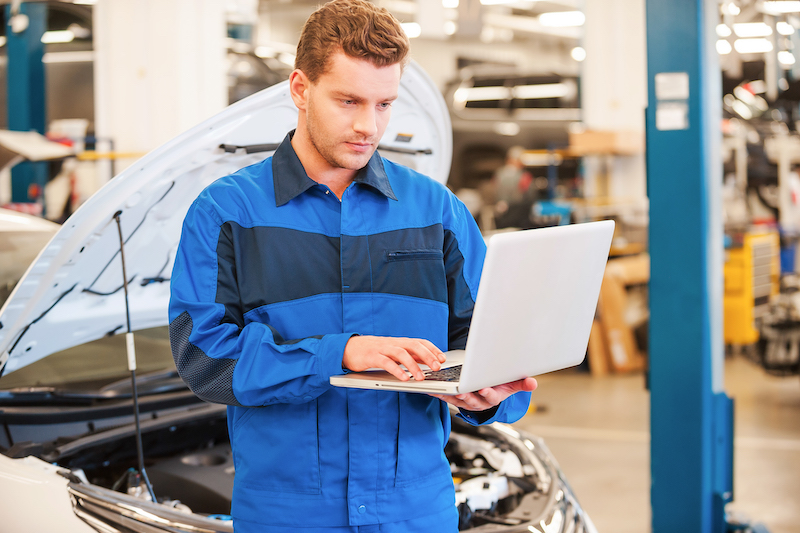 mechanic in automotive workwear with laptop