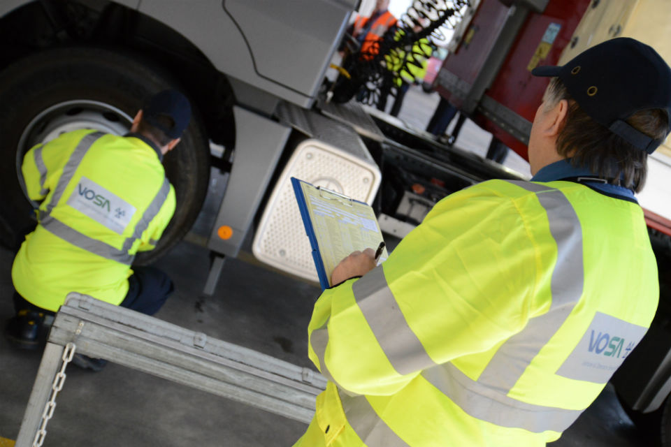 driver in high vis uniform checking lorry tyres