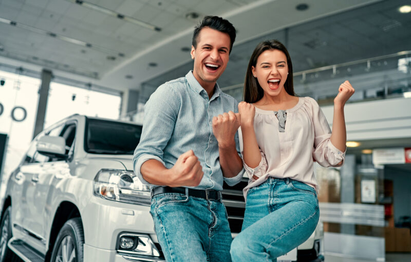 excited couple in car dealership